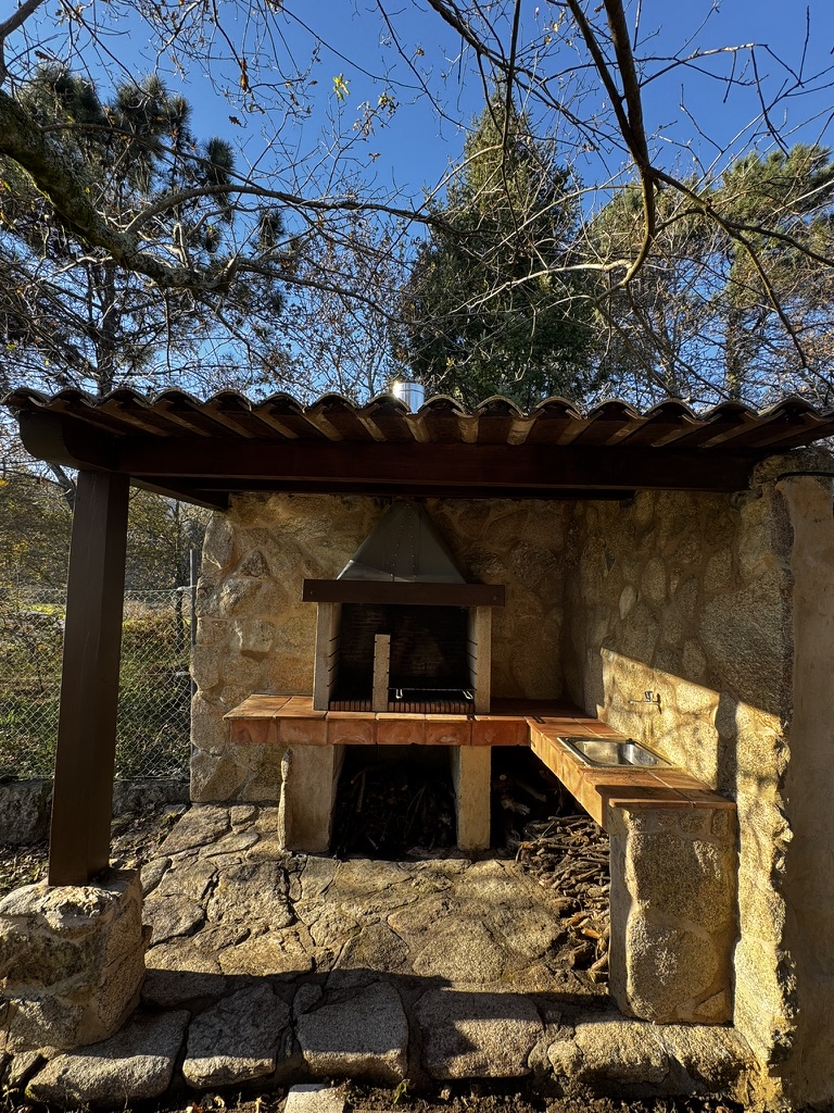 Barbacoa de granito con tejado cerámico en el jardín de Enriba Do Portal