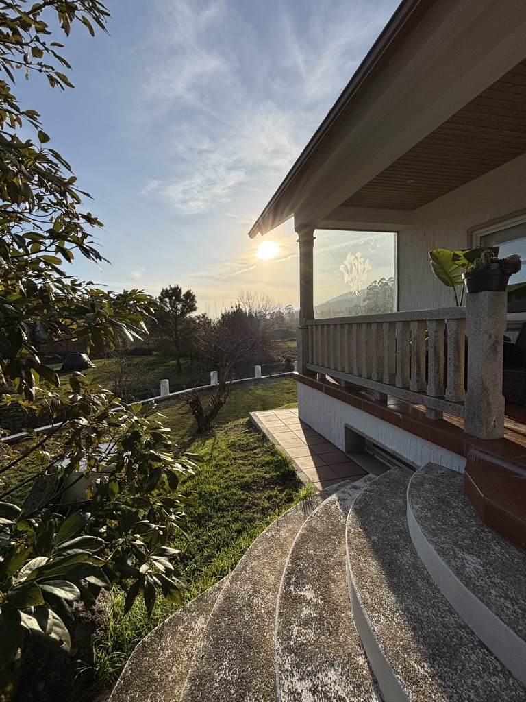 Terraza cubierta de Enriba Do Portal con columnas de granito y vistas al jardín al atardecer